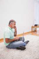 Mature man sitting on rug using laptop