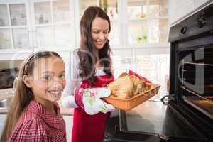 Smiling mother and daughter with roast turkey