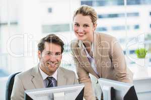 Smiling businessman helping his colleague at a computer