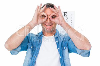 Smiling man with fingers around his eyes