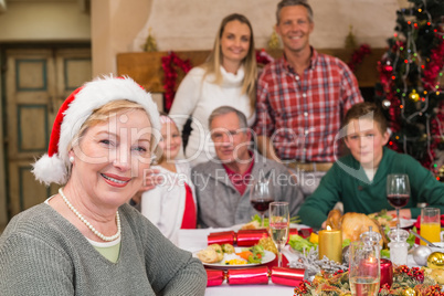 Cute grandmother in santa hat posing in front of her family