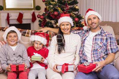 Festive family posing with gifts on the couch