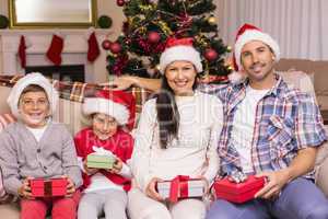 Festive family posing with gifts on the couch