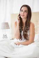 Pretty brunette talking on the phone in bed