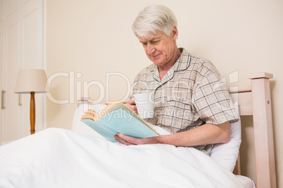 Senior man reading a book in bed