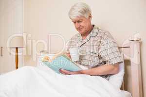 Senior man reading a book in bed