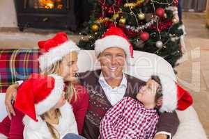 Festive family in santa hat hugging on couch