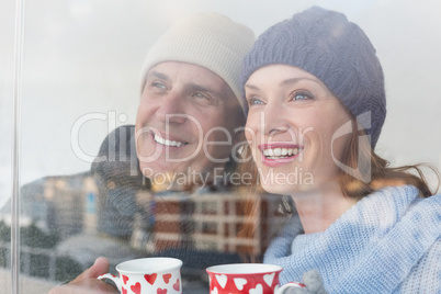 Happy couple in warm clothing holding mugs