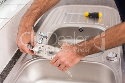 Man fixing tap with pliers