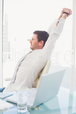 A businessman stretching in swivel chair