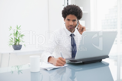 Businessman in shirt phoning and taking notes