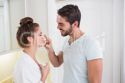 Young man putting cream on girlfriends nose