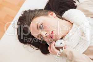Pretty brunette making a phone call on bed