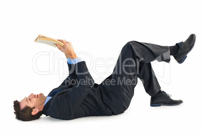 Businessman lying on the floor while reading a book