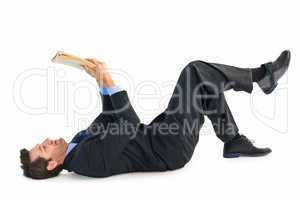 Businessman lying on the floor while reading a book