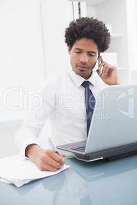 Serious businessman phoning and taking notes