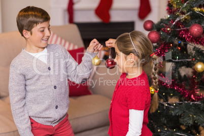 Brother and sister decorating the christmas tree with baubles