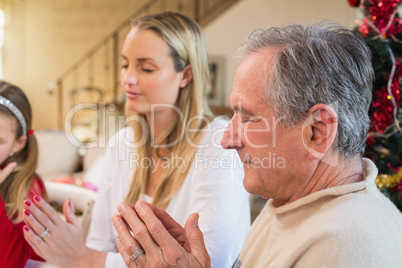 Extended family saying grace before christmas dinner