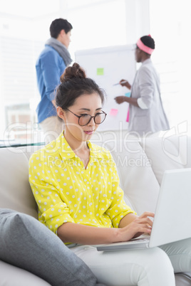 Young creative woman using laptop on couch