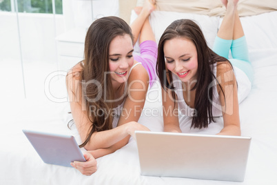 Pretty friends using their technology on bed