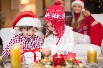 Festive little girl opening a gift with brother