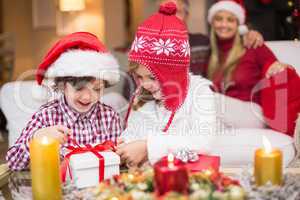 Festive little girl opening a gift with brother