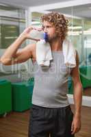 Handsome man drinking water at gym