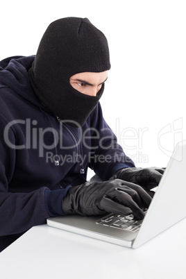 Focused hacker in balaclava hacking laptop