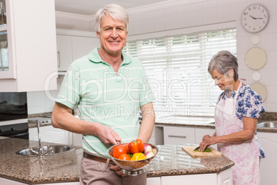 Senior man showing colander of vegetables