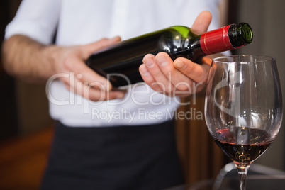 Waiter pouring a bottle of red wine