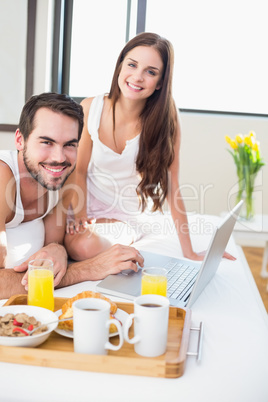 Young couple having breakfast in bed