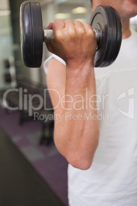 Fit man lifting heavy black dumbbell