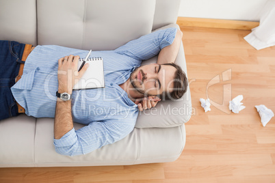 Casual man lying on couch with crumpled papers