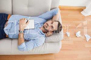 Casual man lying on couch with crumpled papers