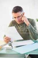 Cheerful man with glasses reading paper