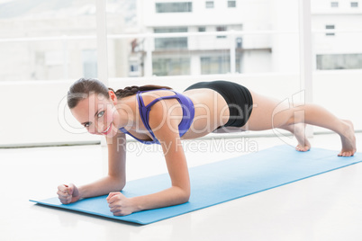 Fit brunette doing pilates on exercise mat