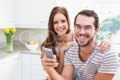 Young couple smiling at the camera man holding smartphone