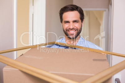 Happy man carrying moving box and frame