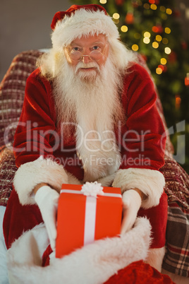 Cheerful santa claus holding present