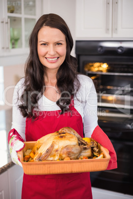 Happy brunette holding her roast turkey