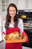 Happy brunette holding her roast turkey