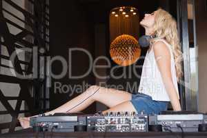 Sexy DJ girl with eyes closed sitting behind the decks