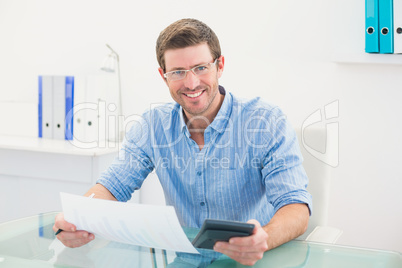 Smiling businessman working on his finances at his desk