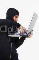 Burglar with balaclava hacking a laptop