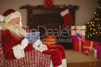 Santa using tablet on the couch at christmas