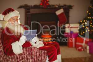 Santa using tablet on the couch at christmas