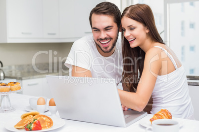 Young couple using laptop at breakfast