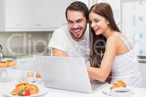 Young couple using laptop at breakfast