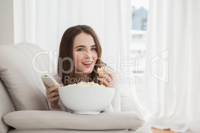 Pretty brunette watching tv with popcorn