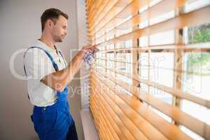 Handyman cleaning blinds with a towel